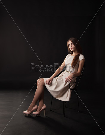 young beautiful girl in a bright dress sitting on the chair