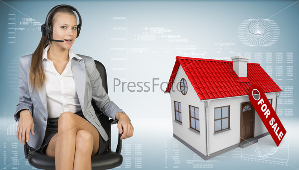 Businesswoman in headset sitting on office chair, looking at camera, speaking. Model house with tag for sale beside. Hi-tech graphs with various data as backdrop