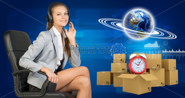 Businesswoman in headset, Globe, commodity boxes and alarm-clock beside