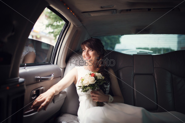 Smiling bride looking out the window of the car, stock photo