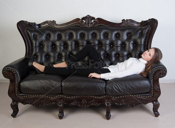 Pretty girl lying on a leather sofa