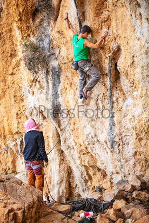 Man lead climbing on cliff, belayer watching hi