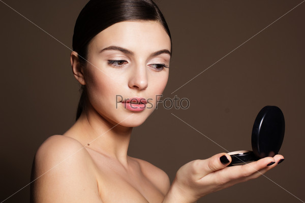 Portrait of a naturally beautiful woman is holding powder that makes skin flawless and perfect, stock photo