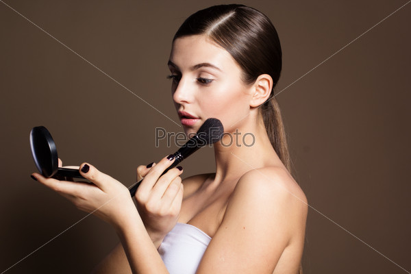 Portrait of a naturally beautiful woman is holding brush and powder that makes skin flawless and perfect, stock photo