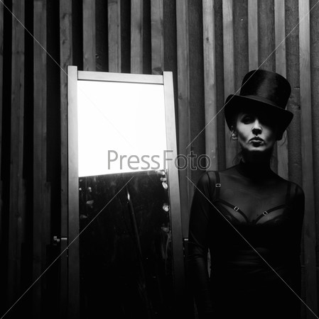 Beautiful young woman wearing a high hat near the mirror . Retro style