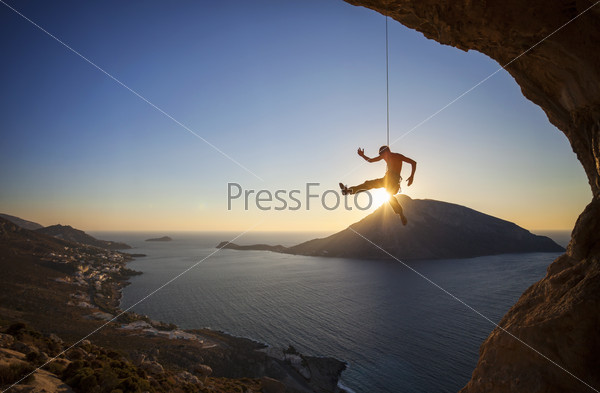 Male rock climber falling of a cliff at sunset