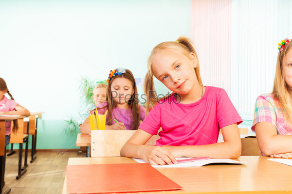 Girl sits at desk with elbows on exercise book