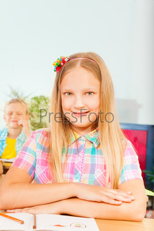 Girl sits at desk with hands on exercise book