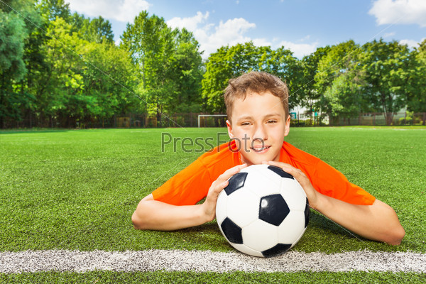 Smiling boy holding football with both arms