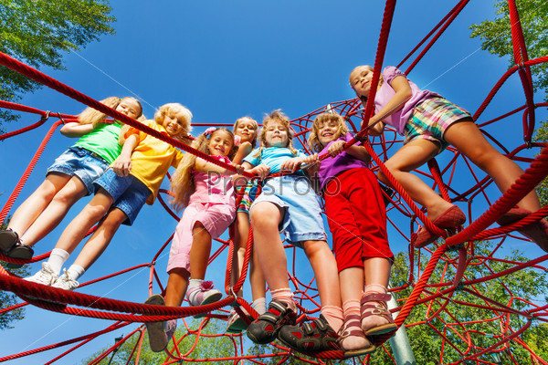 Children stand close on ropes of playground net