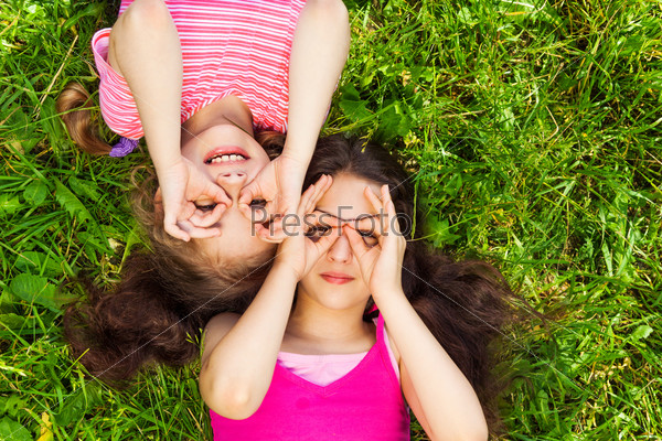 Two girls with hands round shape on face