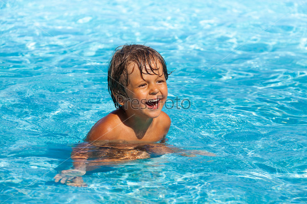 Laughing boy with positive emotions swim in pool