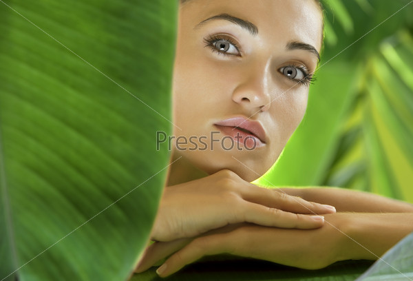 Молодая красивая женщина на фоне зеленых листьев