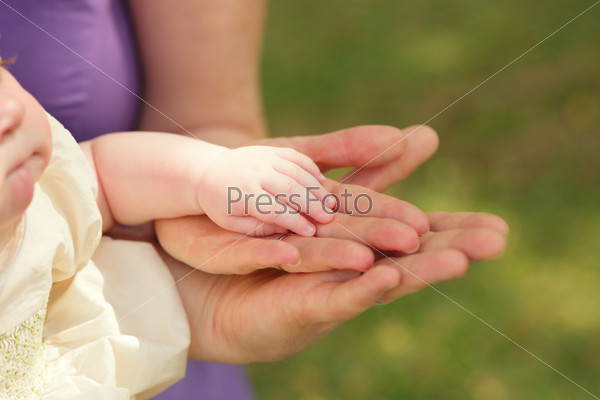 Hands of baby and her parents: protection, support, love and family concept