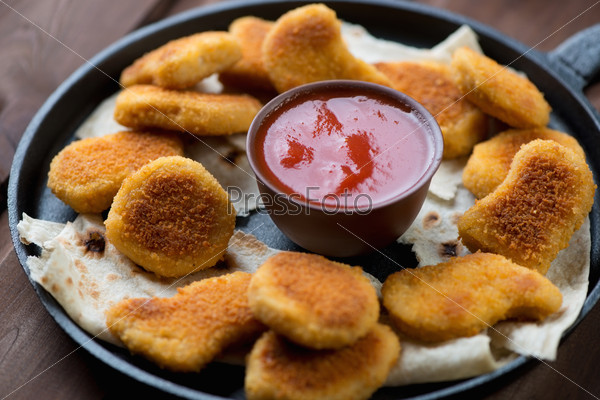Frying pan with nuggets and dip sauce, close-up, studio shot