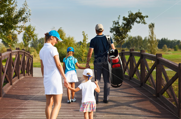 Family of golf players walking in the golf club