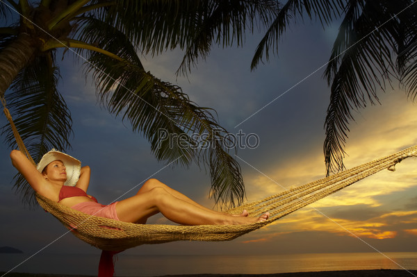 view of a woman lounging in hammock after sunset
