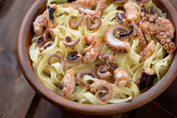 Close-up of tagliatelle with sliced octopus, selective focus