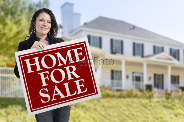 Smiling Hispanic Female Holding Sold For Sale Sign In Front of Beautiful House.
