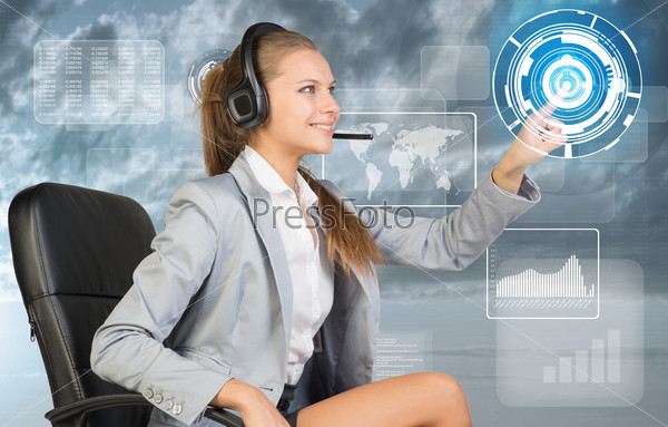 Businesswoman in headset sitting on chair using virtual interface. World map, graphs and figures over cloudy sky as backdrop