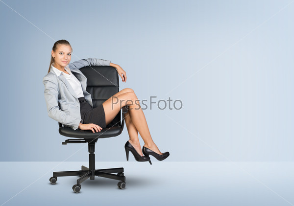 Businesswoman sitting on office chair in empty room, looking at camera