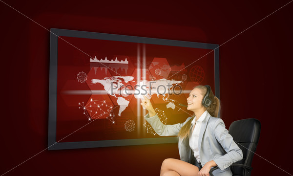 Businesswoman in headset using touch screen interface with world map, graphs and other elements, on red background