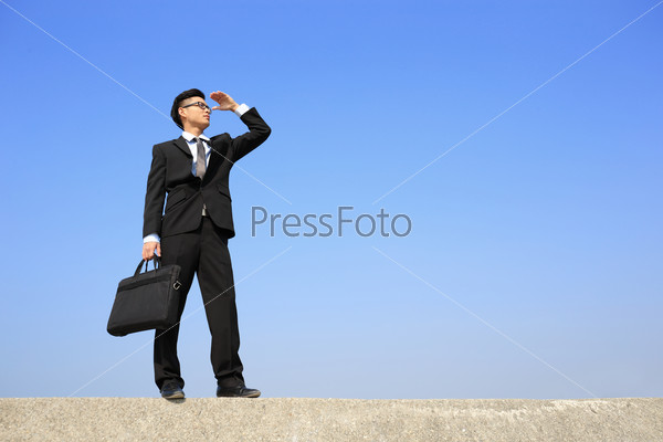 Successful business man purposefully looking away with blue sky, asian male