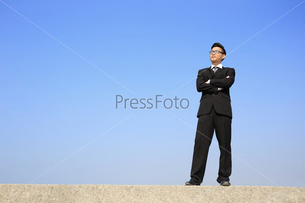 Successful business man purposefully looking copy space in the image with blue sky, asian male