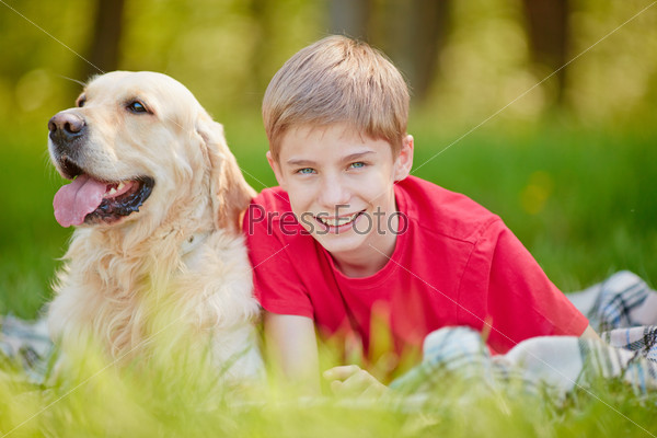 Happy boy with his pet relaxing in grass , stock photo
