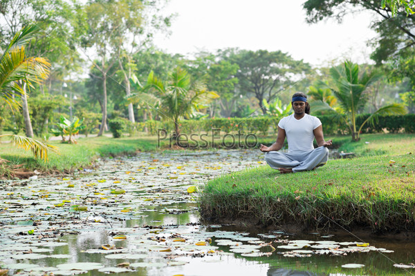 Man meditating in park near the river