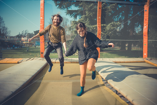 young modern stylish couple urban city jumping trampoline outdoors