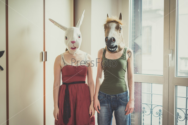 Mask rabbit and horse mask lesbian couple at home, stock photo