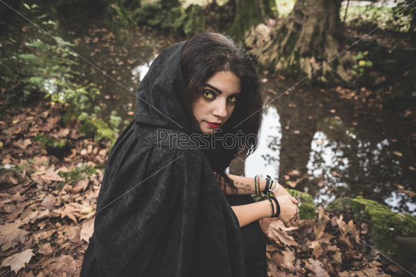beautiful dark vampire woman with black mantle and hood halloween