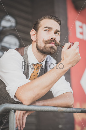 handsome big moustache hipster man smoking pipe in the city