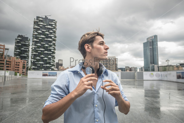 young model hansome blonde man with music headphones in the\
city