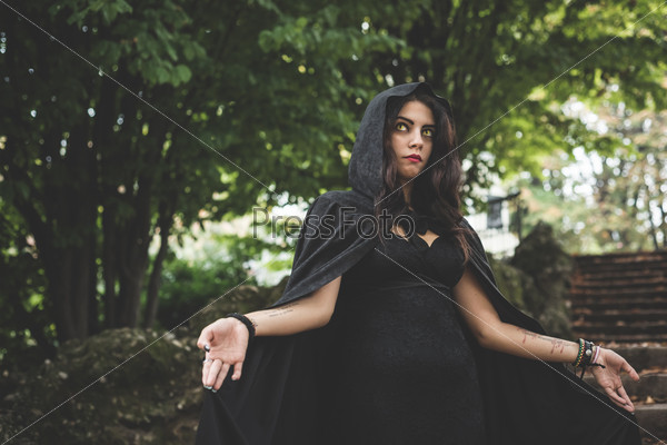Beautiful dark vampire woman with black mantle and hood halloween, stock photo