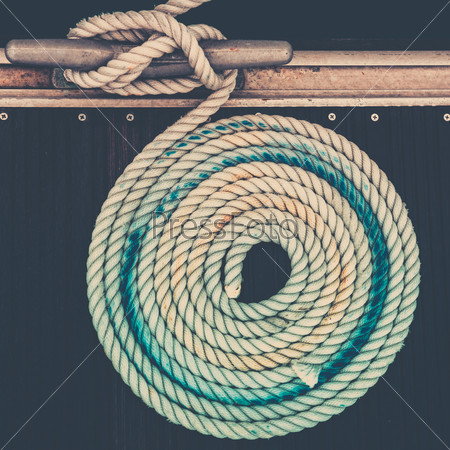 Mooring rope with a knotted end tied around a cleat on a pier