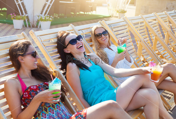 Girls with beverages on summer party near the pool