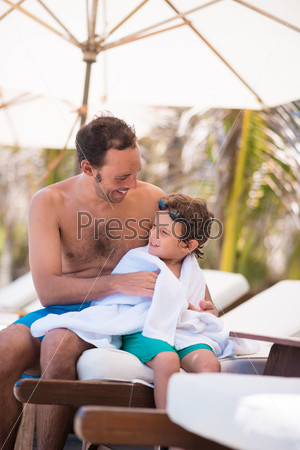 Cheerful father and son drying after swimming pool