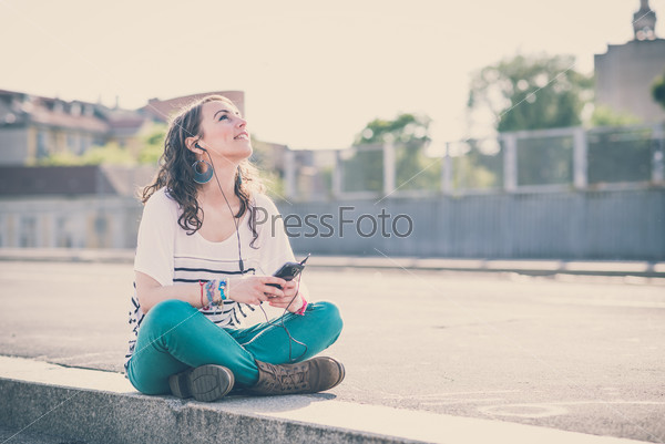 young beautiful brunette woman with smart phone listening\
music in the city