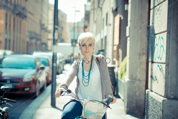Beautiful young blonde short hair hipster woman witk bike in the city, stock photo