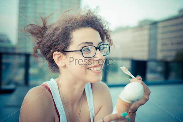 young beautiful long curly hair hipster woman eating ice cream in the city