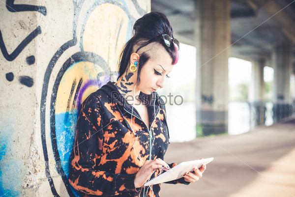 Young beautiful punk dark girl using tablet in urban landscape, stock photo