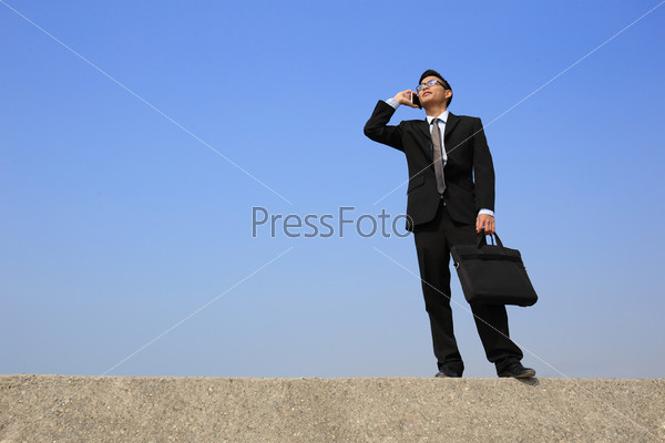 Successful business man speak phone with blue sky, asian male