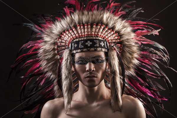 Portrait of the indian strong man posing with traditional native american make up