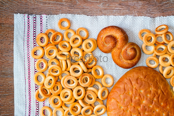 On the surface of the table on a linen napkin are bagels, bread and rolls. View from the top.