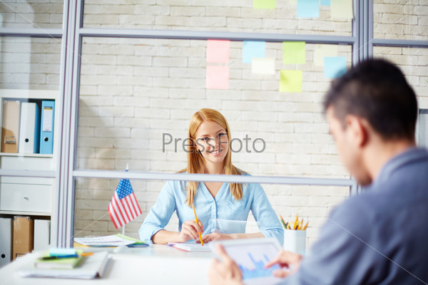 Young businesswoman looking at co-worker at meeting in office