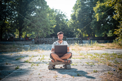 Young stylish man using notebook at the park, stock photo