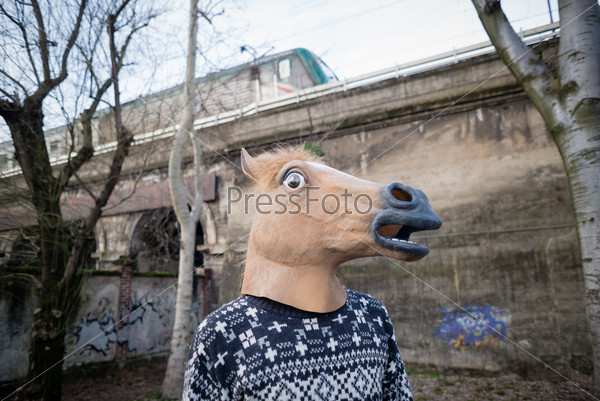 young hipster man horse mask at the park