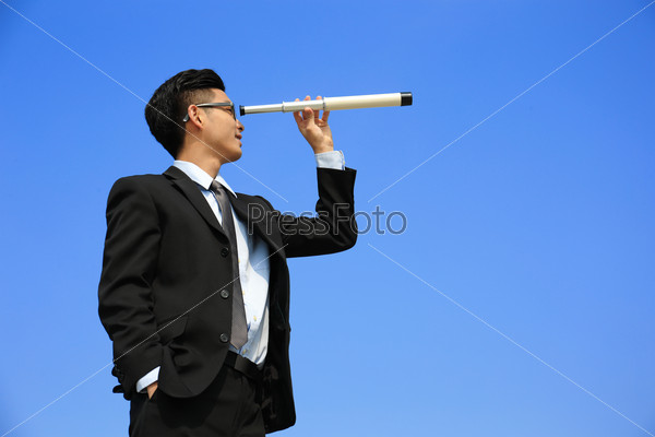 Businessman with telescope ( spyglass ) looking forward Prospects for future business with blue sky background, asian